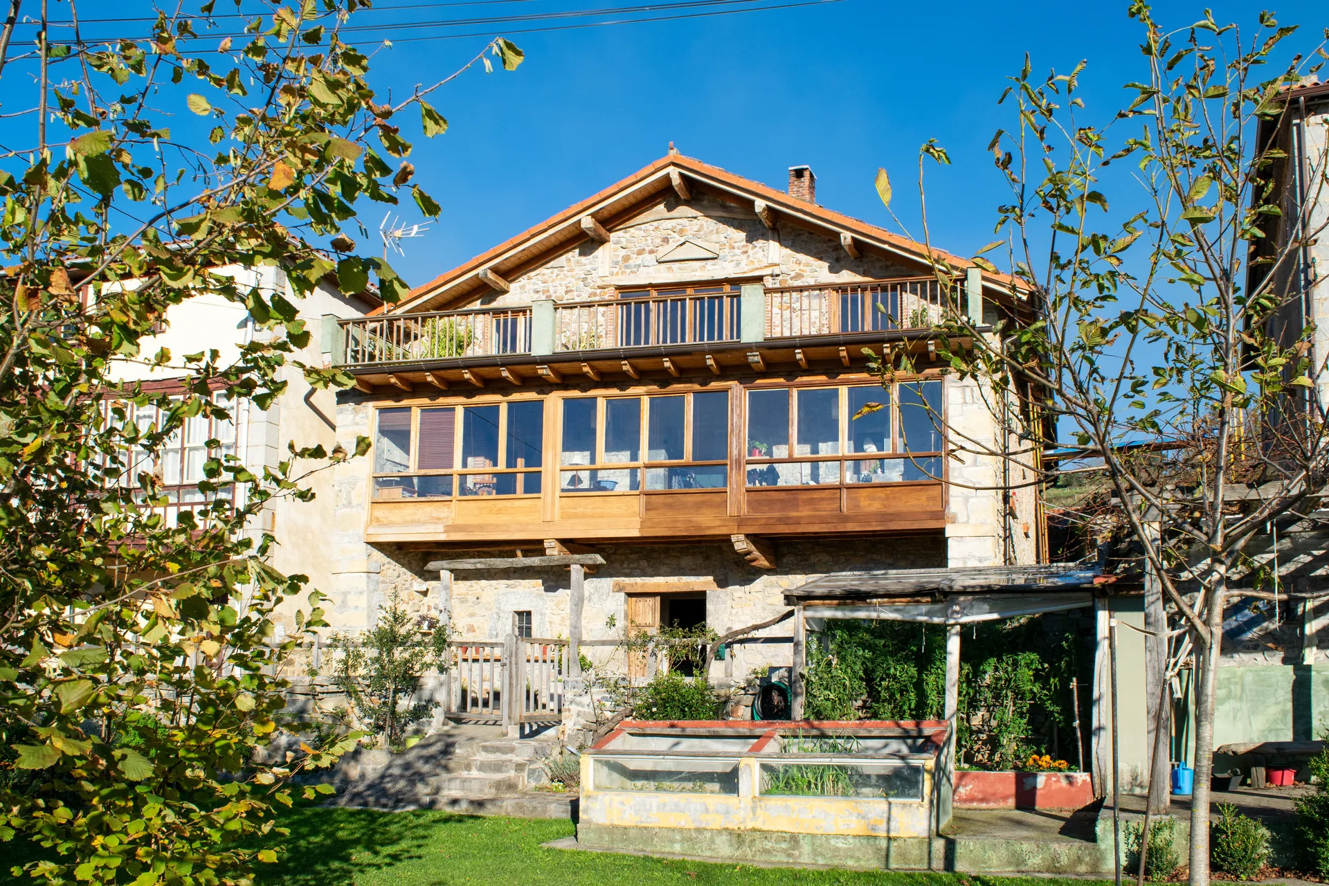 South-facing stone facade of Casa de Aja with restored masonry and traditional wooden balcony